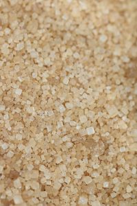 Close-up of cane sugar (raw sugar), displaying its characteristic light golden color and larger crystal size, ready for further refining or industrial use.