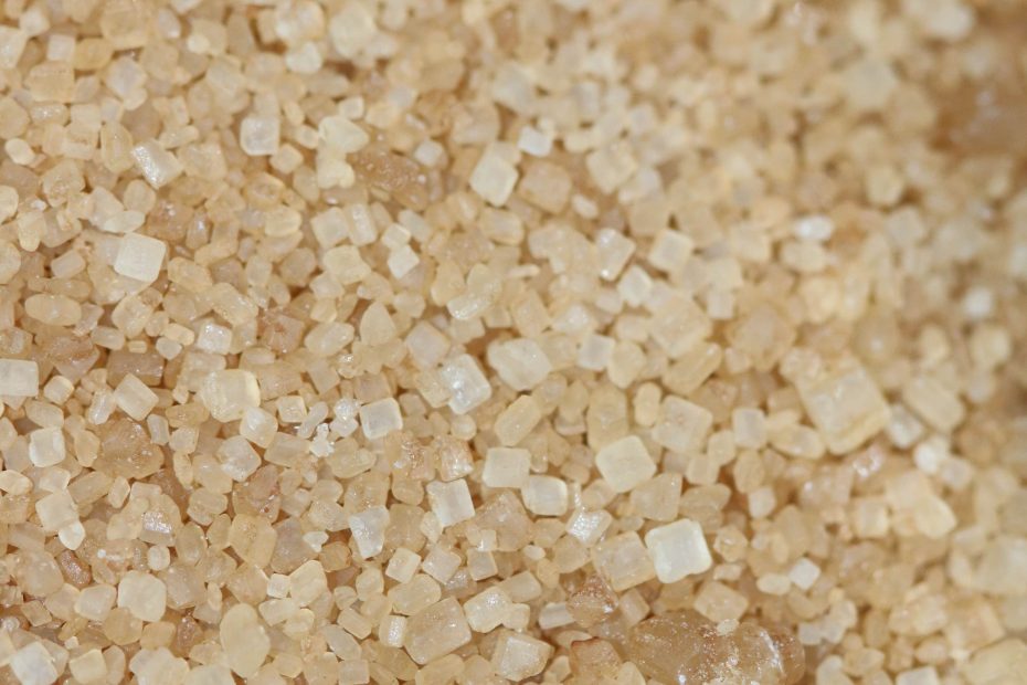 Close-up of cane sugar (raw sugar), displaying its characteristic light golden color and larger crystal size, ready for further refining or industrial use.