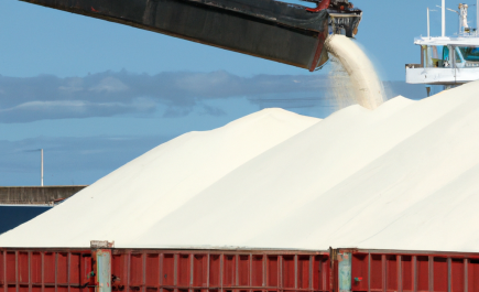 Refined white sugar being loaded into a barge for transport, illustrating the bulk handling process of sugar logistics.